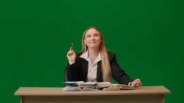 Beyin fırtınası ve problem çözme konsepti. Krom anahtar yeşil ekranda kadın portresi. Masada oturan bir sürü kitapla hayal kuran, fikir bulan, parmağını kaldıran, kafasında lamba yanan bir kız..