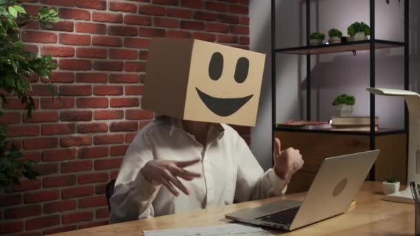 ビジネスライフとオフィスの日常的なクリエイティブ広告コンセプト 頭に絵文字が入った段ボール箱の女性の肖像 ラップトップでビデオ通話で話す机に座っている労働者 幸せな顔 — ストック動画