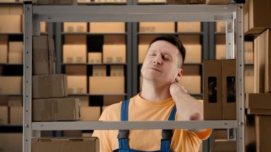 İş deposu ve lojistik yaratıcı reklam konsepti. Depoda çalışan erkek portresi. Rafların yanında duran adam yorgun yüz masajı yapan boynu işten sonra ağrıyan biri..