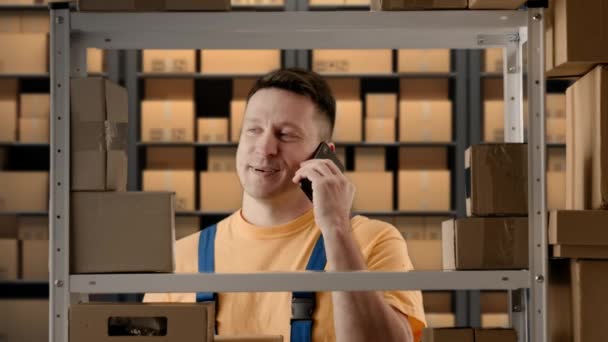 商务仓储和物流创意广告理念 男性在储藏室工作的肖像 店主站在货架旁边 用智能手机谈论订单 脸上挂着积极的微笑 — 图库视频影像
