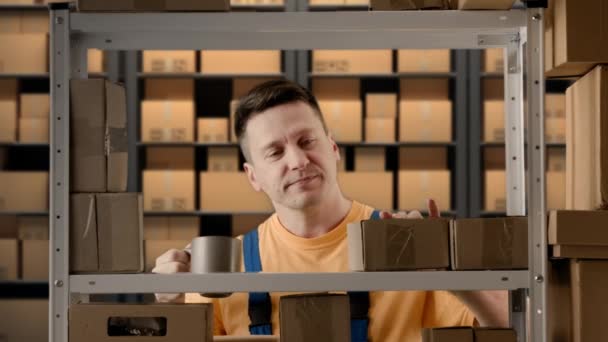 ビジネス倉庫と物流クリエイティブ広告コンセプト 倉庫で働く男性の肖像画 パッケージを見ているマグカップからコーヒーを飲むラックの近くに立っている男のストーリーキーパー — ストック動画