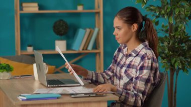 Evinde dizüstü bilgisayarla çalışan ve kahve içen bir kadını orta ölçekte çekmiş. Engelli kadın programcı, tekerlekli sandalyede hareket sorunu olan iş kadını. Uzak iş, modern yaşam tarzı.