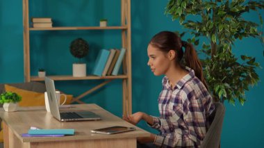 Bir kadını videoya çekerken orta ölçekli bir fotoğraf. Ev bilgisayarındaki biriyle konuşurken. Genç bayan programcı, iş kadını çalışıyor. Uzak iş, modern yaşam tarzı.