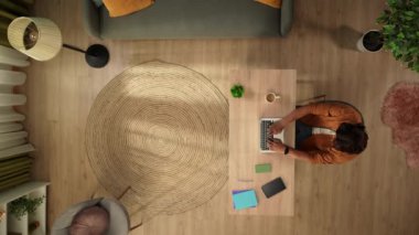 Üst görüntüde, evinde dizüstü bilgisayarla çalışan bir adam görülüyor. Genç işadamına bir telefon geliyor, biriyle konuşuyor, sakin ve huzurlu. Uzak iş, modern yaşam tarzı.