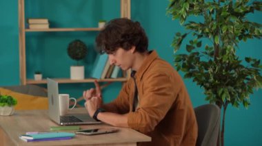 Ofisinde dizüstü bilgisayarla çalışan ve kahve içen bir adamı orta ölçekte çekmiş. Genç erkek programcı, iş adamı, bir proje üzerinde çalışıyor. Uzak iş, modern yaşam tarzı.