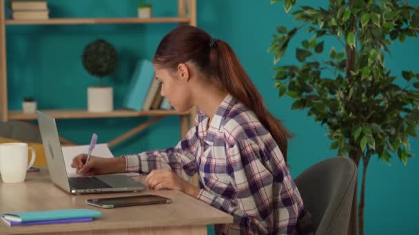 Średnie Ujęcie Kobiety Pracującej Laptopie Swoim Biurze Zapisującej Coś Notatniku — Wideo stockowe
