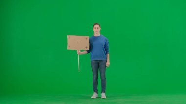 Üzgün bir kadın eylemci yeşil ekranda boş bir tabela tutuyor. Krom anahtar, reklam, tanıtım.
