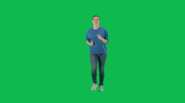Spor ayakkabı giyen, kot pantolon giyen ve yeşil ekranda koşan bir kadın. Uzun boylu bir kadının koşu görüntüsü. Reklam, tanıtım, kroma anahtarı.