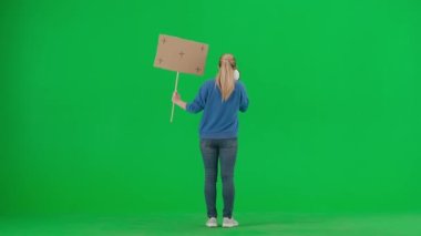 Kameradan uzak duran bir kadın megafona doğru konuşuyor ve elinde boş bir levha tutuyor. Ağızlığı ve plaketi yeşil ekranda olan bir kadının arka planı. Protesto eylemi, kadınlar için mücadele