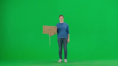 Üzgün bir kadın eylemci yeşil ekranda boş bir tabela tutuyor. Krom anahtar, reklam, tanıtım.