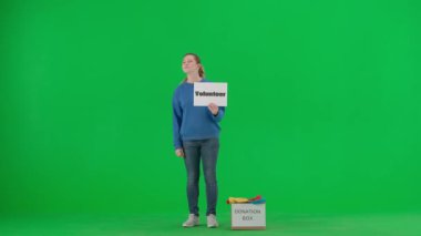 Gönüllü bir kadın yeşil ekrandaki stüdyoda jestini göstermek için elini sallıyor. Kadın, üzerinde 