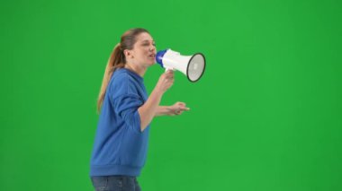 Yumruğunu kaldırmış, stüdyoda megafona bağırarak tehditkar bir şekilde bağıran kadın eylemci. Profesyonel bir protestocu kadının yürüyüşünün yan görüntüsü. Protesto eylemi, kadın hakları için mücadele, grev