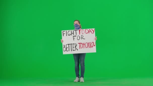 一位女权运动者举着一张标语牌 上面写着 为更美好的明天而奋斗 一个满脸围巾的女人在绿色的屏幕上高喊着标语 — 图库视频影像