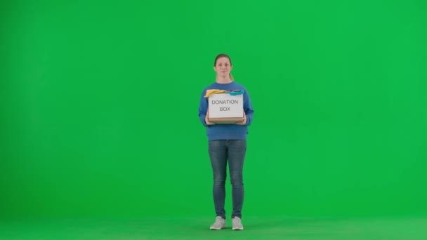 一位女志愿者拿着一个装满衣服的盒子 上面写着捐赠盒 女人伸出盒子 在绿色的屏幕上肯定地点了点头 社会援助 志愿服务 人道主义和 — 图库视频影像