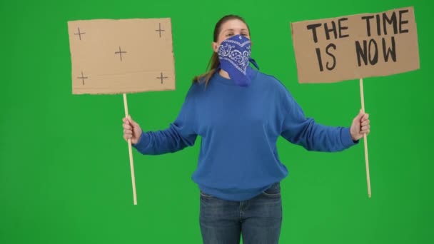 一位脸上蒙着围巾的女性示威者举起一个标牌 上面写着 时间是现在 时间是一个空白的标牌 这个女人在绿色的屏幕上紧闭着高喊口号 — 图库视频影像