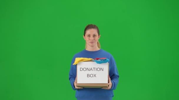 一位女志愿者拿着一个装满衣服的盒子 上面写着捐赠盒 女人伸出盒子 在绿色的屏幕上肯定地点点头 关上了 社会援助概念 志愿工作 — 图库视频影像