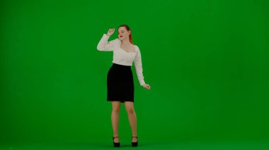 Modern iş kadını yaratıcı reklam konsepti. Krom anahtar yeşil ekranda çekici ofis kızı portresi. Etek ve bluz giymiş bir kadın etrafına bakıyor ve kurnazca dans etmeye başlıyor, gülen surat..