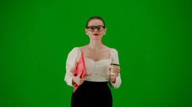 Modern iş kadını yaratıcı reklam konsepti. Krom anahtar yeşil ekranda çekici ofis kızı portresi. Etekli ve gözlüklü bir kadın kırmızı klasör ve kahve fincanı taşıyor, gülümsüyor..