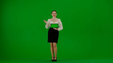Modern iş kadını yaratıcı reklam konsepti. Krom anahtar yeşil ekranda çekici ofis kızı portresi. Etekli kadın elinde tabletle kamera karşısında konuşuyor, reklam servisi.