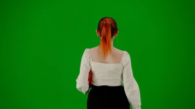 Modern iş kadını. Krom anahtar yeşil ekranda çekici ofis kızı portresi. Etekli ve bluzlu bir kadın kağıt klasörle yürüyor. Yan görünüm.