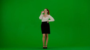 Modern iş kadını yaratıcı reklam konsepti. Krom anahtar yeşil ekranda çekici ofis kızı portresi. Etek ve bluz giyen kadın elinde kağıt bardakla kahve içip kurnazca dans ediyor..