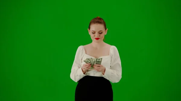 Modern business woman creative advertisement concept. Portrait of attractive office girl on chroma key green screen. Woman in skirt and blouse walking and counting money, happy face expression.