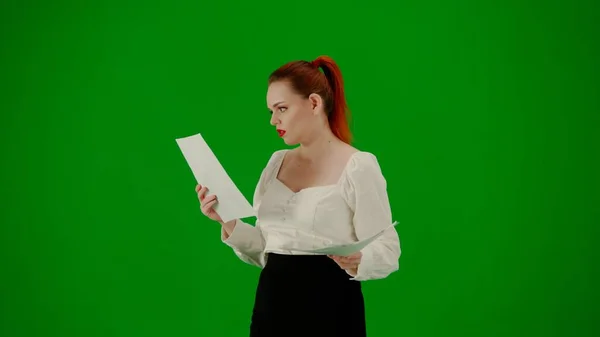 现代商业女性 色键绿色屏幕上漂亮的办公室女孩的肖像 身着短裙和女衫的女人一边走路一边阅读纸质文件 一边专注地表现自己的面部表情 转半圈 — 图库照片