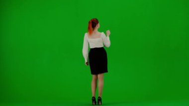 Modern iş kadını yaratıcı reklam konsepti. Krom anahtar yeşil ekranda çekici ofis kızı portresi. Etekli ve bluzlu kadın sanal menüyü kullanıyor, bakıyor ve araklıyor..