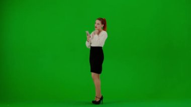 Modern iş kadını yaratıcı reklam konsepti. Krom anahtar yeşil ekranda çekici ofis kızı portresi. Etek ve bluz giyen kadın elinde akıllı telefon ve mesajlaşma, mutlu yüz ifadesi..