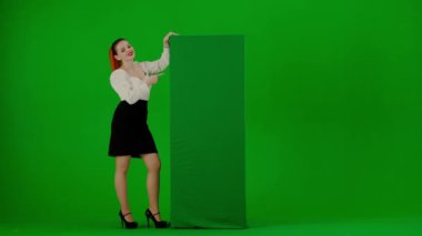 Modern iş kadını yaratıcı reklam konsepti. Krom anahtar yeşil ekranda çekici ofis kızı portresi. Yeşil reklam panosuna bakan etekli ve bluzlu kadın, baş parmağını kaldırıyor..