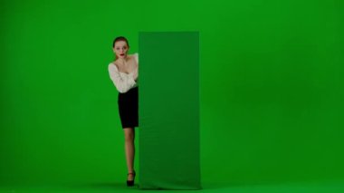 Modern iş kadını yaratıcı reklam konsepti. Krom anahtar yeşil ekranda çekici ofis kızı portresi. Etek ve bluz giymiş bir kadın reklam panosunun arkasına bakıyor..