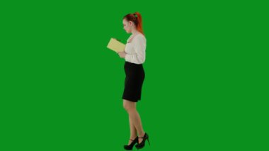 Modern iş kadını. Krom anahtar yeşil ekranda çekici ofis kızı portresi. Etek ve bluz giyen bir kadın elinde defterle yürüyor ve fikirler yazıyor, odaklanmış bir yüz. Yan görünüm.