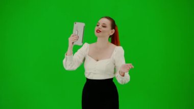 Modern iş kadını yaratıcı reklam konsepti. Krom anahtar yeşil ekranda çekici ofis kızı portresi. Etekli ve bluzlu kadın tabletten video çağrısı ile konuşuyor, olumlu ifade..