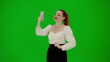 Modern iş kadını. Krom anahtar yeşil ekranda çekici ofis kızı portresi. Etekli ve bluzlu kadın cep telefonuyla video görüşmesiyle konuşuyor, olumlu ifade.