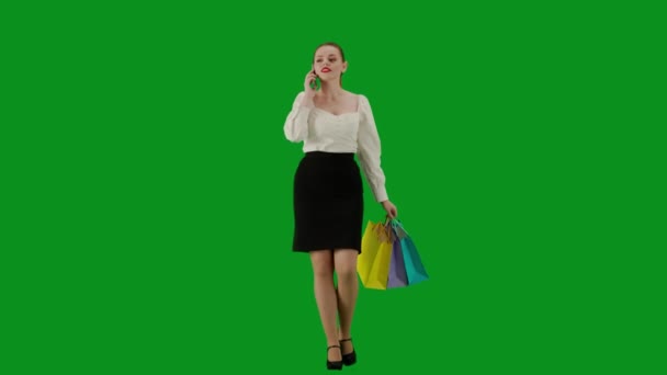 现代商业女性创意广告理念 色键绿色屏幕上漂亮的办公室女孩的肖像 裙子上的女人拿着礼品袋走着 一边用智能手机说话 一边笑着 — 图库视频影像