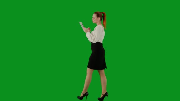 現代のビジネス女性クリエイティブ広告コンセプト クロマキーグリーンスクリーンの魅力的なオフィスガールの肖像画 スカートとブラウスウォーキングの女性 タブレットにテキストを保持しています サイドビュー — ストック動画