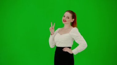 Modern iş kadını yaratıcı reklam konsepti. Krom anahtar yeşil ekranda çekici ofis kızı portresi. Etek ve bluzlu kadın kameraya gülümsüyor ve zafer işareti gösteriyor..