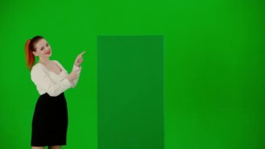 Modern iş kadını yaratıcı reklam konsepti. Krom anahtar yeşil ekranda çekici ofis kızı portresi. Etek ve bluzlu kadın yeşil reklam panosuna bakıyor, gülümsüyor..