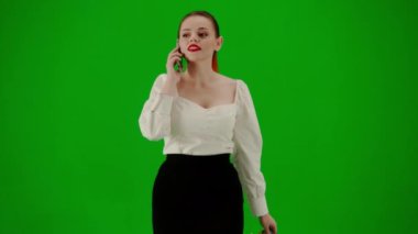 Modern iş kadını yaratıcı reklam konsepti. Krom anahtar yeşil ekranda çekici ofis kızı portresi. Etekli bir kadın elinde hediye çantalarıyla yürüyor ve akıllı telefondan konuşuyor, gülümsüyor..