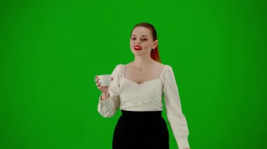 Modern iş kadını yaratıcı reklam konsepti. Krom anahtar yeşil ekranda çekici ofis kızı portresi. Etek ve bluz giyen, gülümseyen, fincandan kahve içen bir kadın..