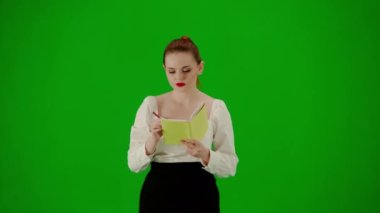 Modern iş kadını yaratıcı reklam konsepti. Krom anahtar yeşil ekranda çekici ofis kızı portresi. Etek ve bluz giyen bir kadın elinde defterle yürüyor ve fikirler yazıyor, odaklanmış bir yüz..