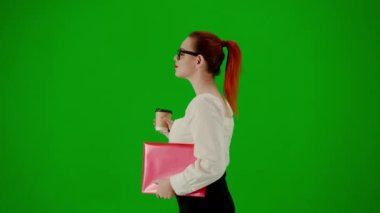Modern iş kadını yaratıcı reklam konsepti. Krom anahtar yeşil ekranda çekici ofis kızı portresi. Kırmızı klasör ve kahve fincanı tutan etekli ve gözlüklü bir kadın. Yan görünüm.