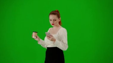 Modern iş kadını. Krom anahtar yeşil ekranda çekici ofis kızı portresi. Etekli ve bluzlu bir kadın kahve içerek yürüyor, akıllı telefondan mesajlaşıyor. Yarım dönüş..
