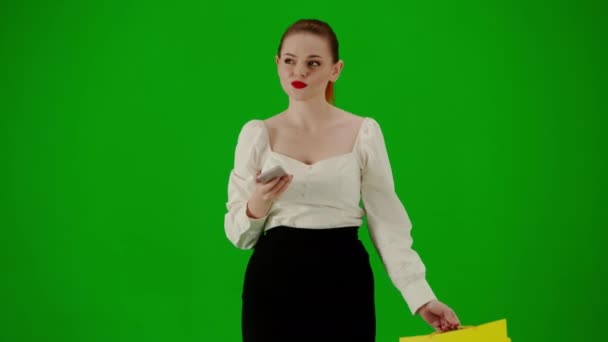 現代のビジネス女性クリエイティブ広告コンセプト クロマキーグリーンスクリーンの魅力的なオフィスガールの肖像画 スカートで歩く女性 ギフトバッグを保持し スマートフォンでテキスト — ストック動画