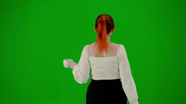 Modern iş kadını yaratıcı reklam konsepti. Krom anahtar yeşil ekranda çekici ofis kızı portresi. Etek ve bluz giymiş bir kadın kupadan kahve içiyor ve yürüyor. Arka plan.