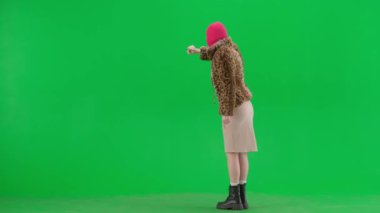 Pembe kar maskeli kadın, kaplan ceketli ve gece elbisesi giyen kadın sanal ekranda geziniyor. Stüdyoda yeşil arka plandaki ucube kadın. Moda eğilimi, feminist moda eğilimi