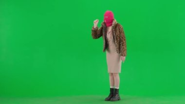 Pembe kar maskeli kadın, kaplan ceketli ve gece elbisesi giyen kadın sanal ekranda geziniyor. Stüdyoda yeşil arka plandaki ucube kadın. Moda eğilimi, feminist moda eğilimi