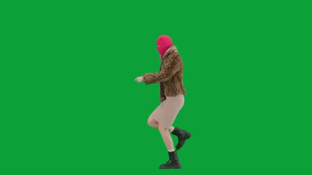 身穿粉色巴拉克拉法帽 虎皮大衣和晚礼服的女人跳着舞跳着跳着跳着 工作室里的女人都是绿色背景的时尚潮流的概念 时尚女性的趋势 — 图库视频影像