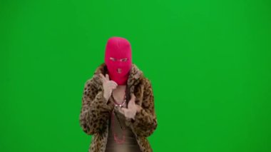 Pembe kar maskeli kadın, kaplan kürkü ve gece elbisesi giyen dans eden ve işaret parmağını farklı yönlere çeviren kadın. Stüdyoda yeşil geçmişi olan ucube kadın.