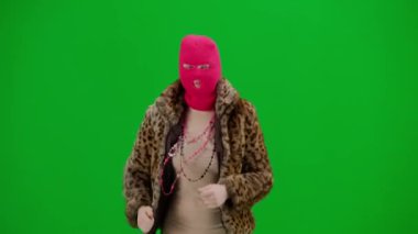 Pembe kar maskeli kadın, kaplan ceketli ve gece elbisesi giymiş. Stüdyoda yeşil arka plandaki ucube kadın. Moda eğilimleri kavramı, feminist moda eğilimi